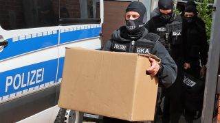 Nach den Durchsuchungen von Räumen im Gebäude "Altes Postamt" kommen die Ermittler mit beschlagnahmtem Material aus dem Haus.