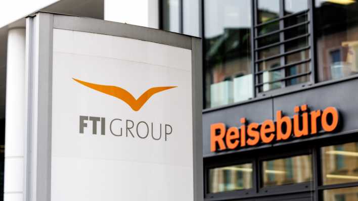 Der Schriftzug "FTI Group" ist auf einer Stele neben einem Reisebüro zu sehen.