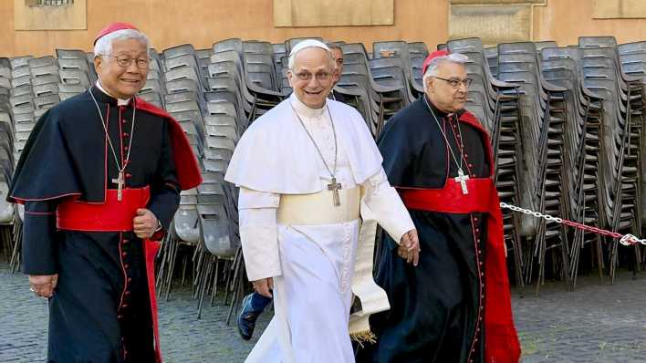 Papst Leo XIV. spaziert durch die Vatikanstadt - an seiner Seite zwei Kardinäle.