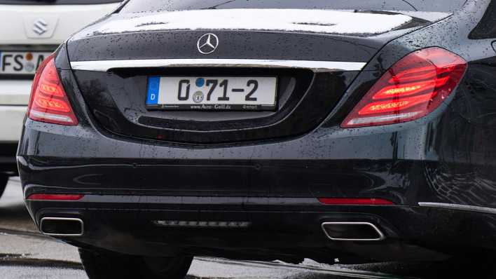 Ein schwarzer Mercedes mit Diplomaten - oder Behördenkennzeichen (0-Nummer) fährt durch eine regennasse Straße.