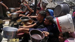 Menschen im Gazastreifen warten mit Töpfen in den Händen auf Nahrungsmittel an einer Gemeinschaftsküche in Jabalia.