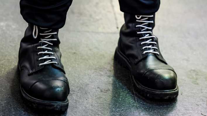 Ein Teilnehmer einer rechtsextremen Kundgebung trägt schwarze Springerstiefel mit weißen Schnürriemen.