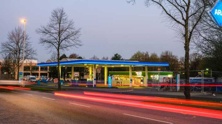 Autos fahren während der Blauen Stunde an einer Tankstelle vorbei.