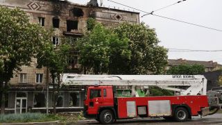 Ein Löschfahrzeug der Feuerwehr steht in Kiew vor einem Gebäude, dass durch einen Luftangriff beschädigt ist.