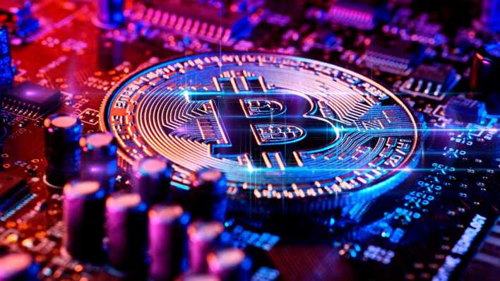 Bitcoin-Münze auf einer Computerplatine (Bild: IMAGO/Christian Ohde)