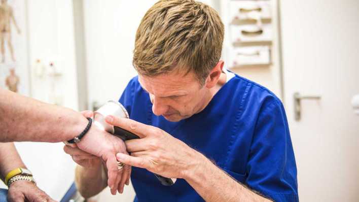 Dermatologe untersucht Haut einer Patientin (Bild: IMAGO/Funke Foto Services/Gerd Wallhorn)