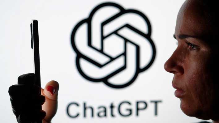 Frau hält ein Smartphone in der Hand, im Hintergrund das Logo von ChatGPT