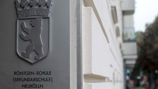 Das Schild der integrierten Sekundarschule ist an der Wand der Röntgen Schule in Neukölln befestigt. (Bild: dpa)
