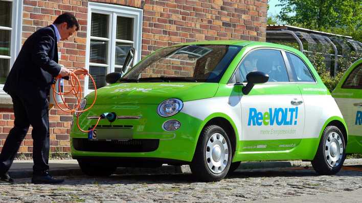 Ein Mitarbeiter schließt am 28.04.2014 auf dem Gelände des Energieversorgers Wemag in Schwerin (Mecklenburg-Vorpommern) ein Elektroauto auf Basis des Fiat 500 zum Aufladen an Stromtankstellen an. Foto: dpa