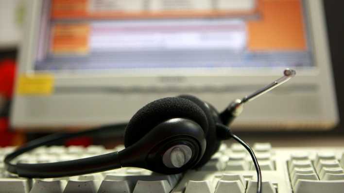 Kopfhörer liegen in einem Call Center auf der Tastatur eines Computers. (Bild dpa)