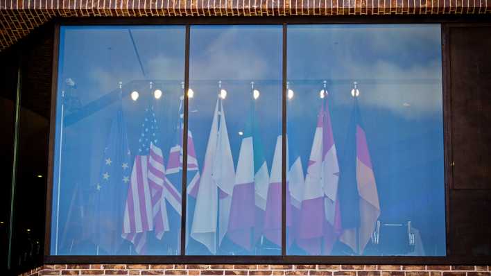 Die Flaggen der G7-Staaten sind in Lübeck (Schleswig-Holstein) hinter einer Scheibe des Konferenzraums zu sehen © dpa
