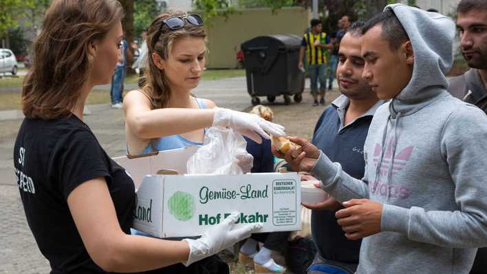 Freiwillige Helfer von "Moabit hilft" versorgen die vor dem Berliner Landesamt für Gesundheit und Soziales auf Bearbeitung ihrer Anträge wartenden Flüchtlinge und verteilen Wasser und Lebensmittel © imago/Christian Mang