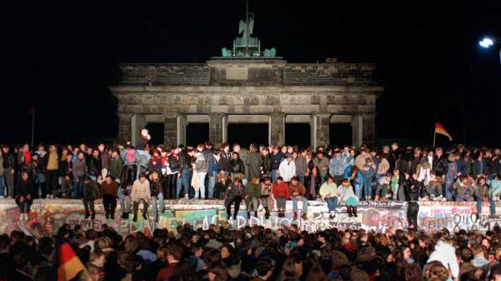 "10.11.1989, Berlin: Jubelnde Menschen auf der Berliner Mauer am Brandenburger Tor"; © Wolfgang Kumm/dpa