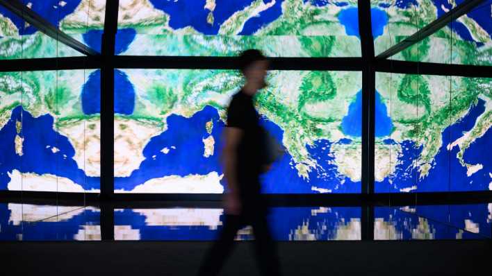 Ein Mann geht zwei Tage vor dem Start der Internationalen Luft- und Raumfahrtausstellung auf dem Gelände vom Flughafen Berlin Brandenburg (BER) im Space Pavillon an einer Wand mit großen Bildschirmen vorbei. (Bild: dpa-news/Bernd von Jutrczenka)