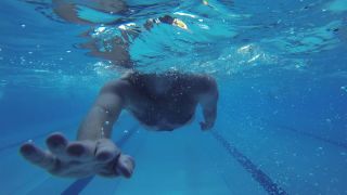 Die Kamera ist unter Wasser und man sieht eine Hand, die sich in Richtung der Kamera streckt. Dahinter ist ein Körper, doch man sieht den Kopf nicht, da er aus dem Wasser ragt.(Quelle:rbb)