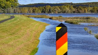 28.09.2024, Brandenburg, Neurüdnitz: Das Hochwasser des deutsch-polnischen Grenzflusses Oder strömt hinter einem deutschen Grenzpfahl an einem Deich vorbei (Quelle: dpa/Patrick Pleul)