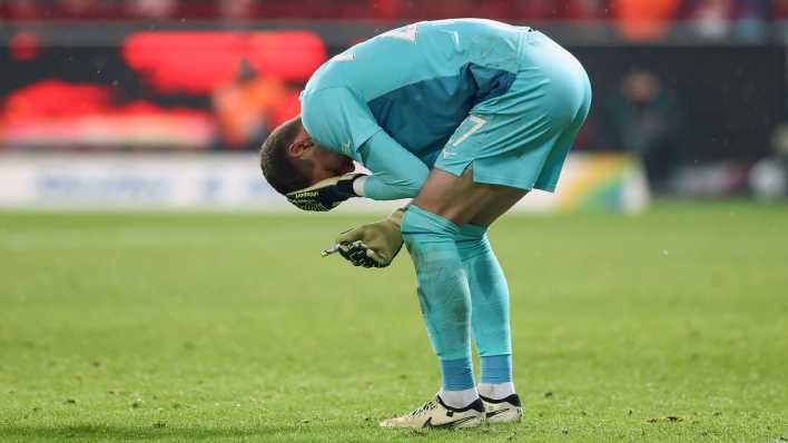 Bochum-Torhüter Patrick Drewes steht gebeugt auf dem Platz, hält sich mit einer Hand den Kopf und mit der anderen ein Feuerzeug, mit dem er in der Nachspielzeit im Bundesliga-Spiel beim 1. FC Union Berlin getroffen wurde (Bild: Imago Images/Jan Huebner)