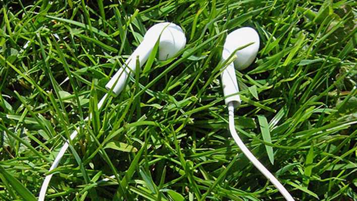 Weiße MP3-Player-Kopfhörer in grünem Gras (Foto: sandralette l photocase.com)